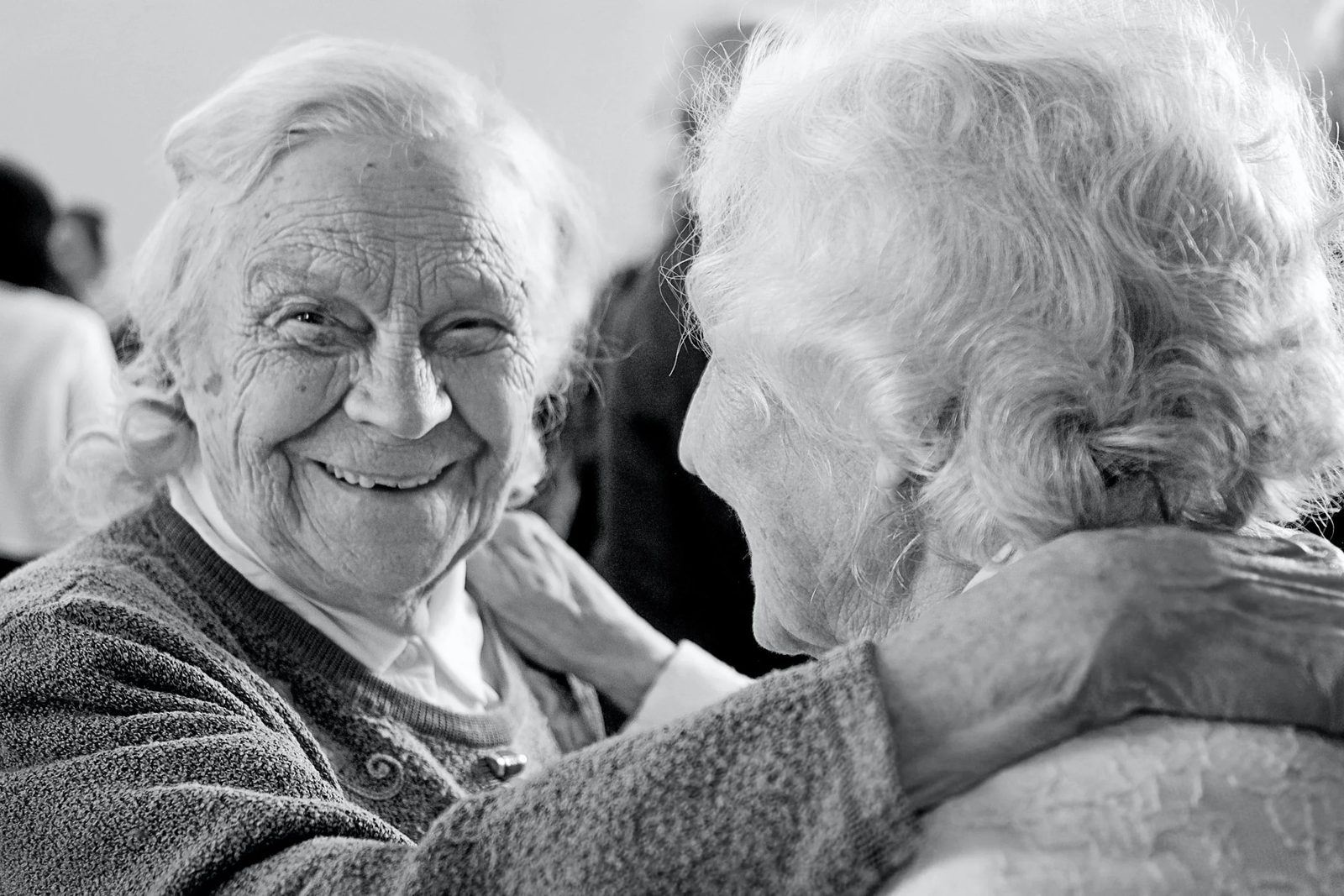 Two smiling older women sharing a hug
