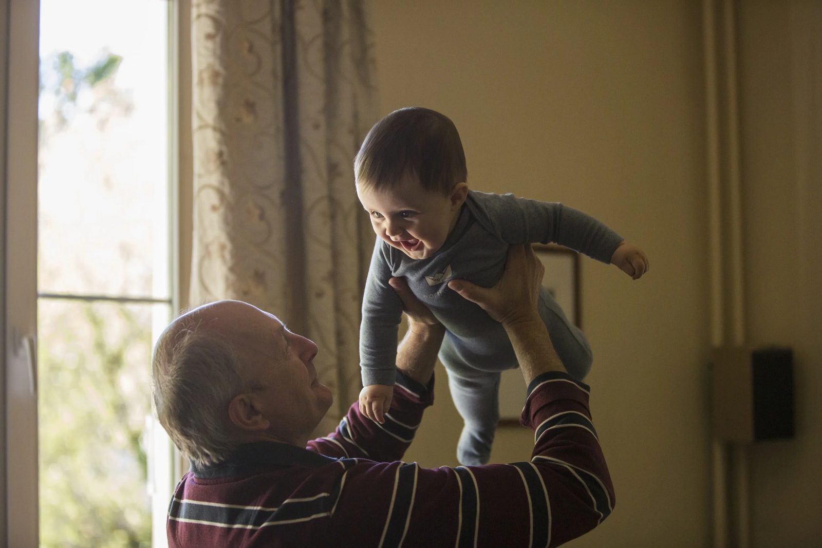 A grandfather lifting his laughing grandson