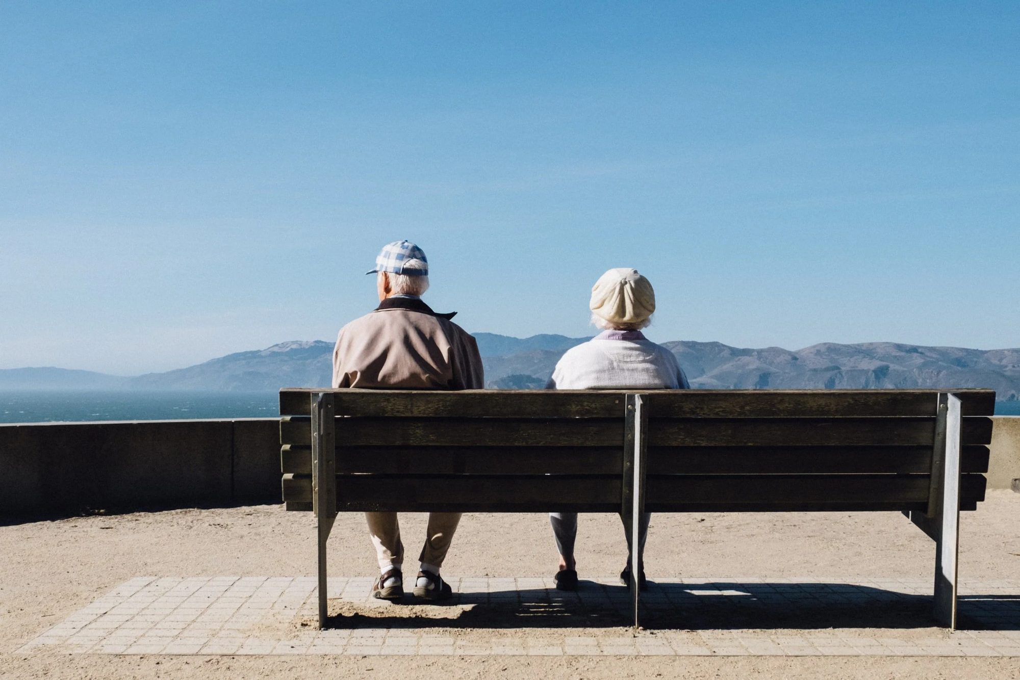 A retired couple sitting on a bench overlooking the bay